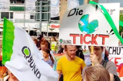 Demonstration mit Umweltplakaten und BUND-Flagge.