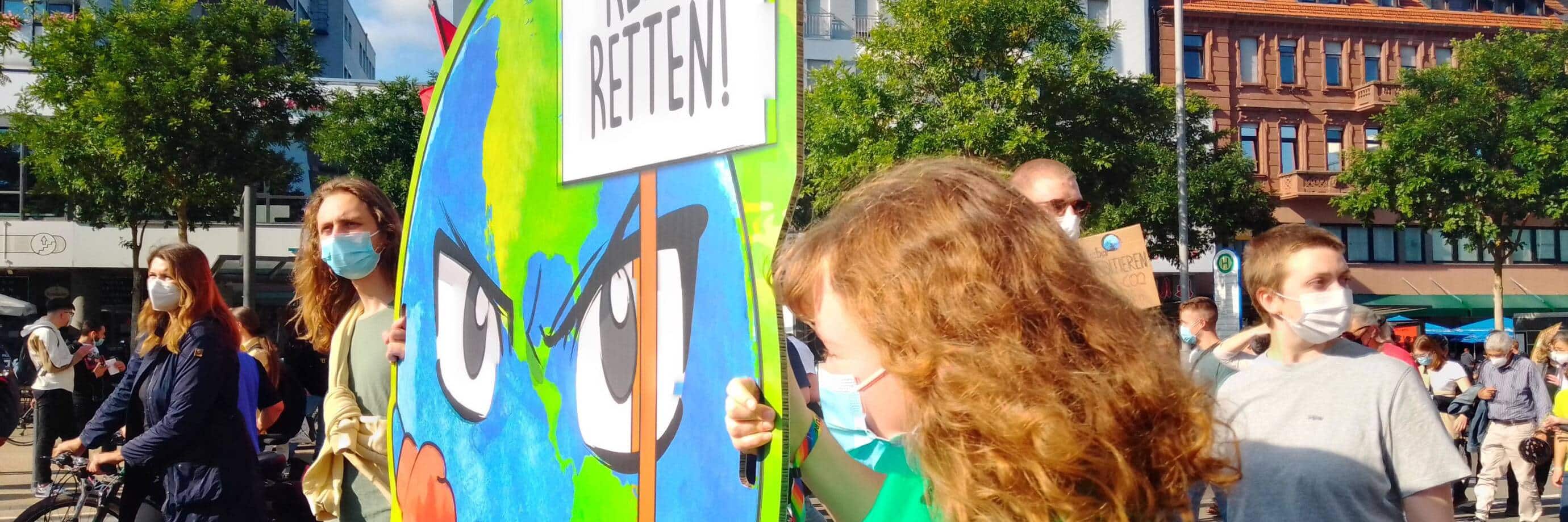 Menschen protestieren mit Plakaten zur Klimarettung.