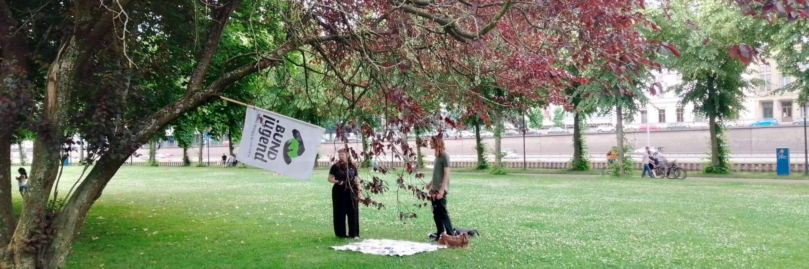 Menschen mit BUND Jugend Flagge im Park